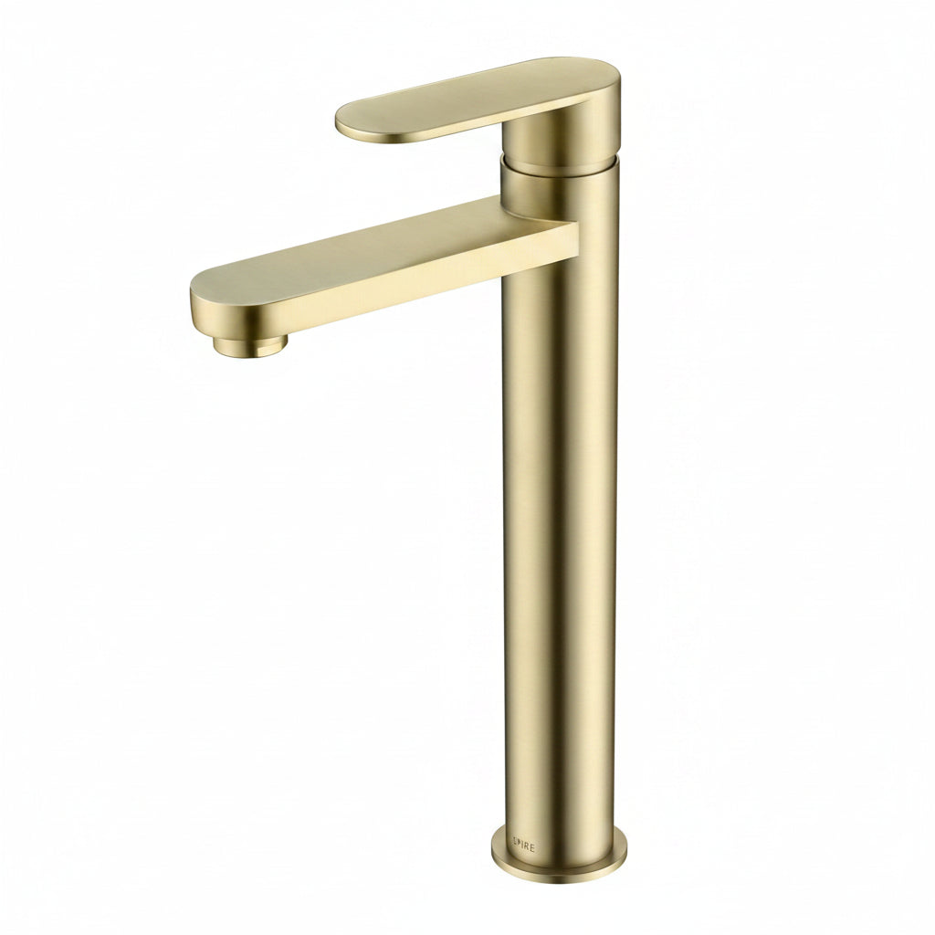 Luxury brushed gold tall basin mixer tap on a natural stone vanity in a warm Scandinavian minimalist bathroom with soft sunlight.